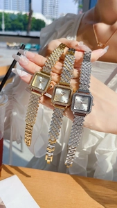 Detailed view of women's square quartz watches with full diamond accents in gold and silver