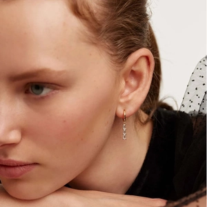 Close-up of gold drop earrings featuring three vertical rectangular cubic zirconia stones