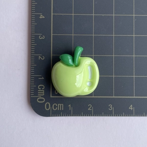 Glossy green apple resin charm shown next to a ruler for 2cm size scale reference