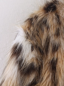 Macro shot of faux leopard fur texture showing detailed brown and white synthetic fibers