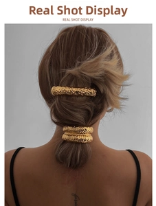 Detailed view of gold metal elastic hair tie with hammered texture on female model