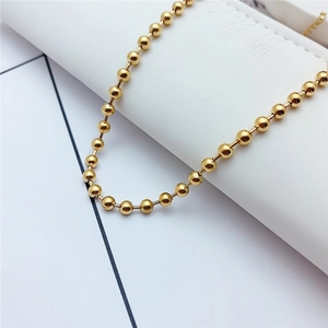 Detailed view of glossy golden beaded chain necklace on textured white background