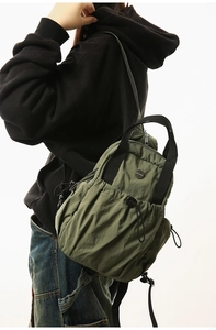 Detail of army green nylon backpack showing large capacity drawstring pocket and side zipper
