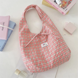 Detail of pink and green plaid tote bag with a small bow and white embroidered label