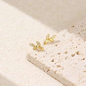 Macro di orecchini a foglia dorata con piccoli diamanti su sfondo in pietra
