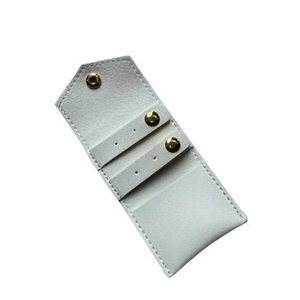 Macro detail of white microfiber jewelry pouch with three gold metal snap buttons