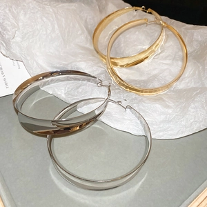 Macro detail of large flat gold and silver hoop earrings with polished mirror finish