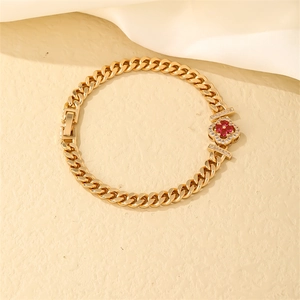 Detail of gold Cuban chain bracelet with red clover gemstone and cubic zirconia accents
