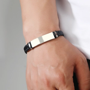 Close-up of a men's braided leather bracelet with a polished silver metal plate on wrist