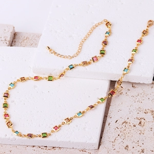 Detail of 18K gold-plated necklace featuring square colorful zircons on white stone tiles