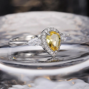 Macro detail of pear-cut yellow gemstone ring with halo diamonds and silver band
