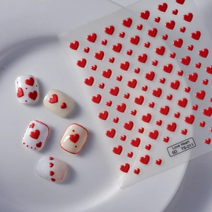 Macro detail of 5D red heart embossed nail stickers showing raised texture on white nails