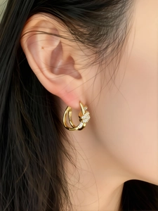 Close-up of gold-plated knotted hoop earring with sparkling cubic zirconia on model