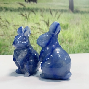 Macro detail of two hand-carved blue natural crystal rabbit figurines in a garden setting