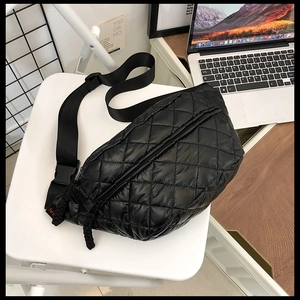 Detail of black quilted nylon belt bag with adjustable strap on a white chair