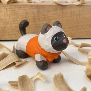 Vue macro d'une figurine de chat siamois en bois sculpté avec un pull orange gravé