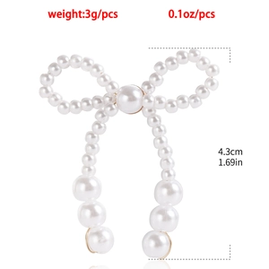 Macro detail of handmade pearl bow earring with elegant fringe tassels and gold hardware