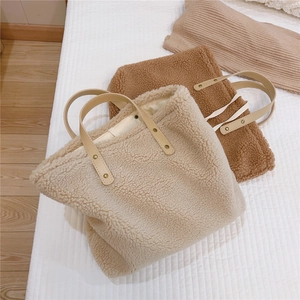 Detail of plush beige and brown sherpa tote bags with leather handles and metal rivets