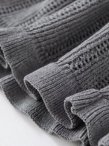 Detailed macro view of gray knitted fabric with crochet patterns and ribbed cuffs texture