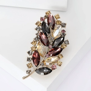 Exquisite crystal feather brooch in gold finish with colorful rhinestones on white stands