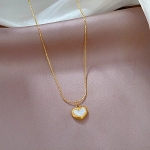 Close-up of a heart-shaped shell pendant on a gold titanium steel necklace chain