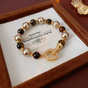 Macro shot of vintage gold-plated bracelet with pearls and tiger eye stone in a jewelry box