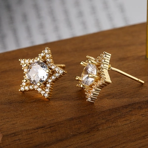 Macro shot of gold-plated star earrings featuring sparkling cubic zirconia on wood