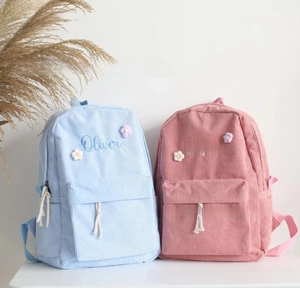 Detail of personalized corduroy backpacks with custom name embroidery and floral decor
