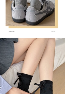 Detail of black mid-calf socks with bow accents paired with grey sneakers for a chic look
