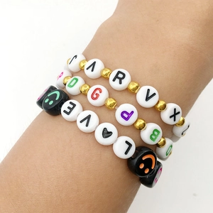Detail of three stacked bracelets with colorful alphabet beads, smiley faces and hearts