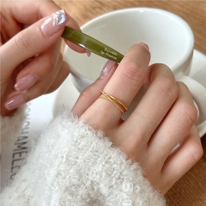 Close-up of a double-layered gold crossover ring styled on a hand with minimal aesthetic