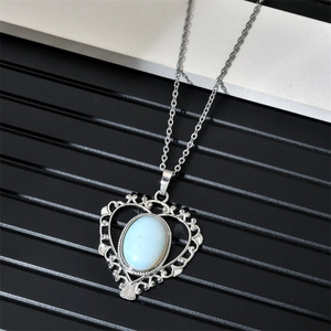 Détail du pendentif cœur argenté avec incrustation d'opale et motifs filigranes