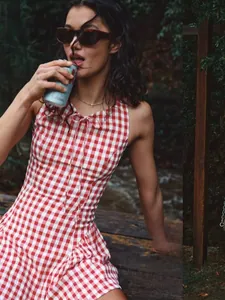 Détail de la robe vichy rouge avec nœud papillon dans un décor extérieur rustique et naturel