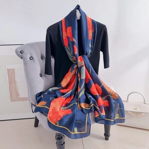 Detail of navy blue silk scarf with orange floral pattern draped on a model