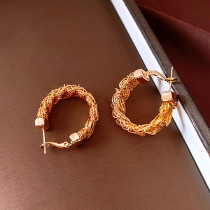 Detailed macro view of 24k gold-plated hoop earrings with intricate woven metal wire texture