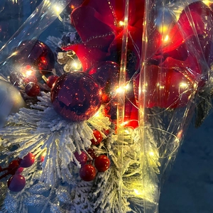 Close-up of Christmas stair garland with red bows, snowy pine needles and warm LED lights