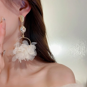 Macro detail of dramatic floral dangle earrings with white silk flowers and crystals