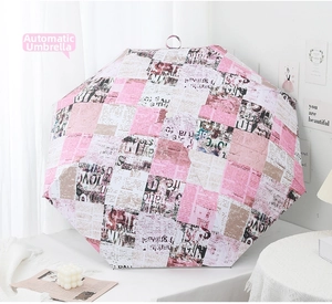 Detail of pink vintage newspaper print automatic umbrella with stylish floral decor
