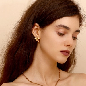 Close-up of model wearing gold starfish earrings with rhinestones and matching chain