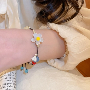 Détail d'un bracelet perlé fleuri avec breloque en argent S925 sur cordon tressé