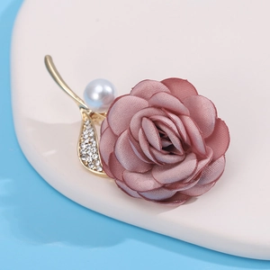 Macro shot of pink fabric rose brooch with gold leaf, rhinestones and white pearl accent
