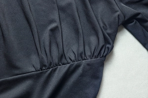Close-up of ruched detailing and elastic pleats on a black elegant slim-fit maxi dress