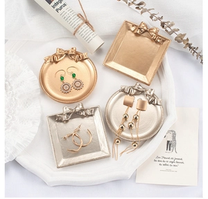 Flachbild von Vintage-Schmuckschalen mit Schleifen in Gold und Silber auf Spitze