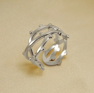 Macro shot of silver layered geometric ring with metal beads on champagne silk fabric