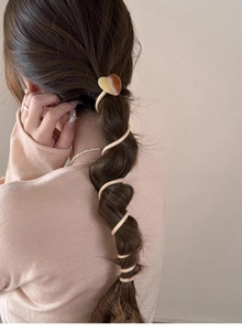 Close-up of heart-decorated spiral hair tie securing a twisted ponytail hairstyle