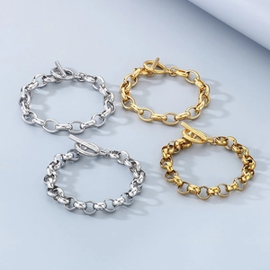 Minimalist OT toggle link bracelets in gold and silver finishes on a solid blue background