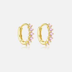 Gros plan de créoles dorées avec zircons roses micro-pavés et finition brillante