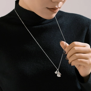 Elegant silver teardrop pendant necklace on black sweater, minimalist chic jewelry for women