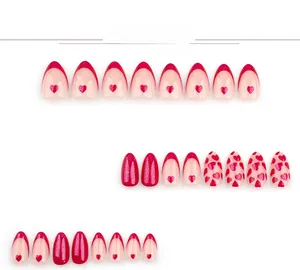 Detail of red and pink press-on nails with heart patterns, glitter, and French tips