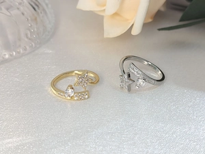 Detailed view of star-shaped micro-pave gold and silver rings on white silk fabric